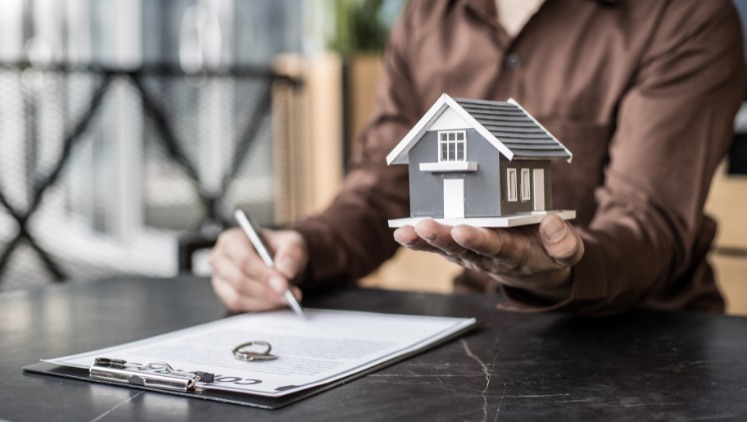 Woman holding real estate and signing a divorce contract